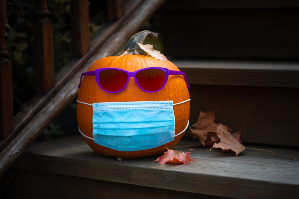 Changing times, changing seasons. Pumpkin with sunglasses and mask on steps